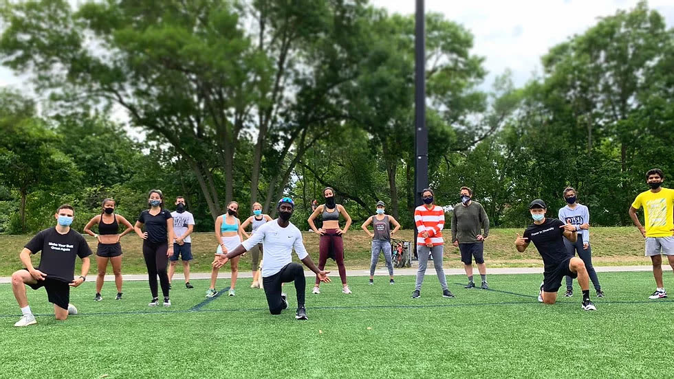 A bootcamp group spread out across a turf field