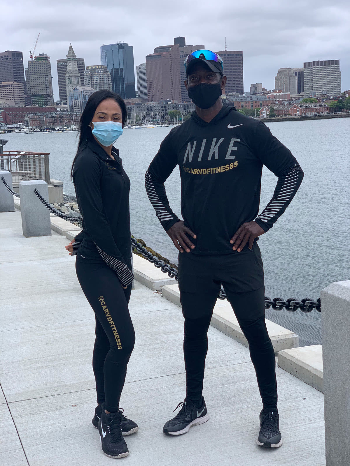 Two Carvd Fitness trainers in black gear on the Boston waterfront